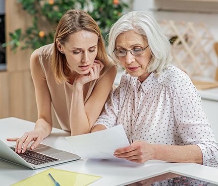 Senior adult woman and her daughter looking over paperwork together
