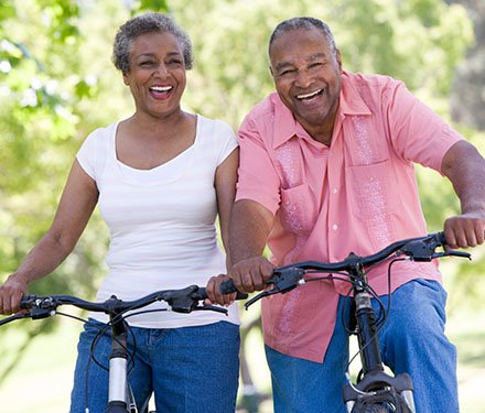 Senior adult couple laughing together as they ride their bikes on a bright sunny day